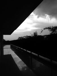 Silhouette trees by bridge against sky