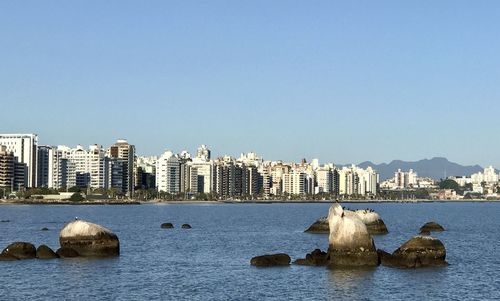 Sea by buildings against clear blue sky