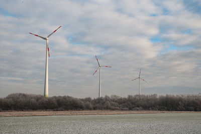 Wind turbines on field against sky