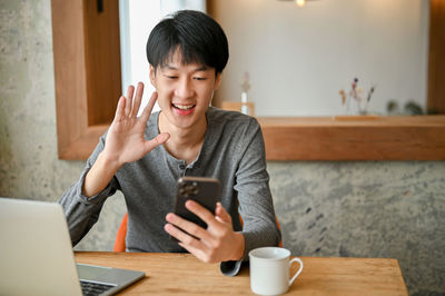 Young woman using mobile phone while sitting on table