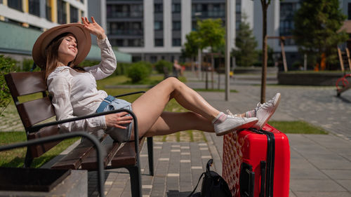 Full length of woman sitting on seat in city