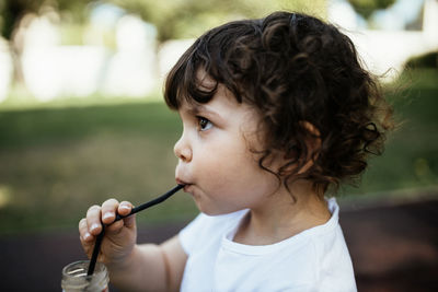 Close-up portrait of cute girl drinking outdoors