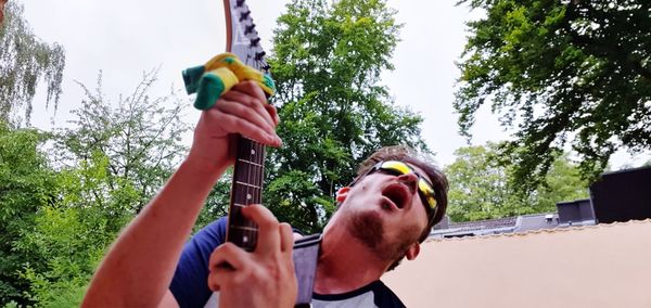 Low angle view of man photographing against sky