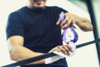 Midsection of man holding paper while standing against wall