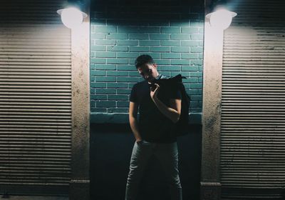 Full length of man standing against illuminated wall of building