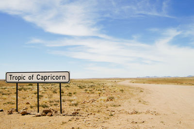 Information sign on desert land against sky