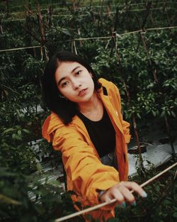 Portrait of young woman standing against plants