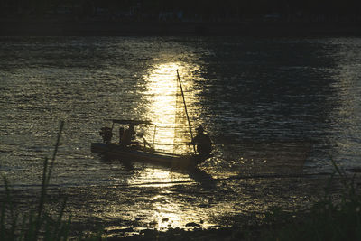 Silhouette people sailing on sea against sky during sunset