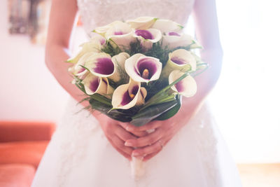 Midsection of bride holding bouquet during wedding
