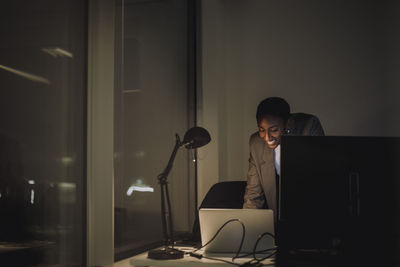 Smiling businesswoman working on laptop last minute at work place