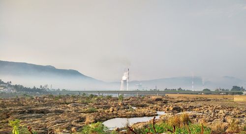 Smoke emitting from chimney on field against sky