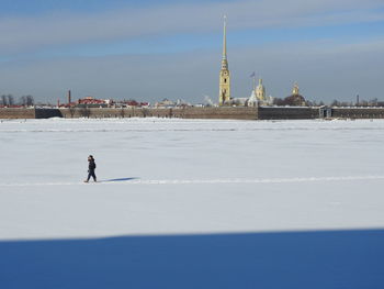 Man walking on snow covered temple against sky