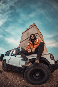 Low angle view of man on car against sky