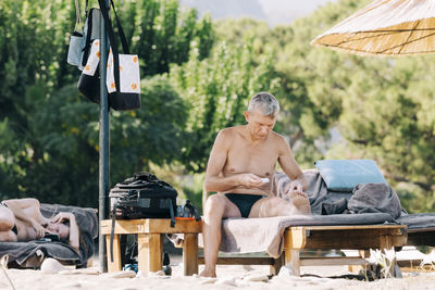 Full length of shirtless man sitting outdoors