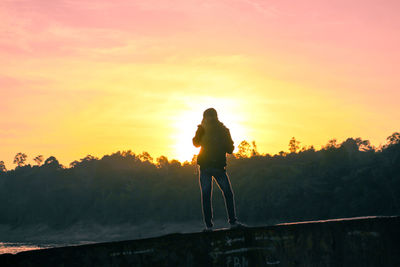 Silhouette man standing on street against sky during sunset