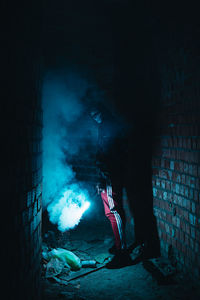 Man standing against illuminated wall at night