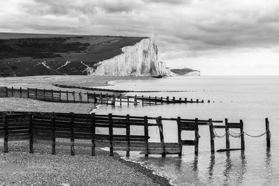 Scenic view of calm beach against cloudy sky