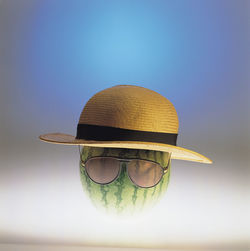 Close-up of watermelon with hat and sunglasses against colored background