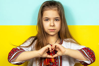 Portrait of young woman standing against wall