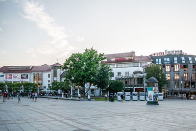 People on city street by buildings against sky