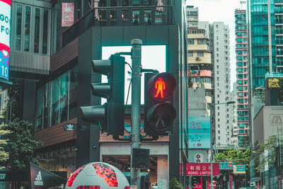 Low angle view of road signal in city against buildings