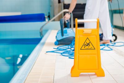 Low section of woman cleaning poolside