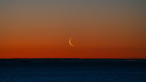 Scenic view of the moon and sea against sky during sunset