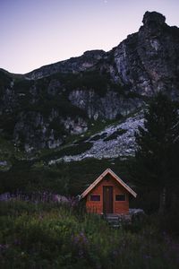 House amidst trees and mountains against sky