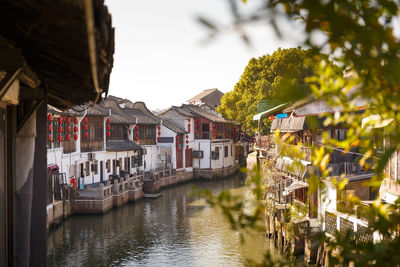 Houses by river amidst buildings in city