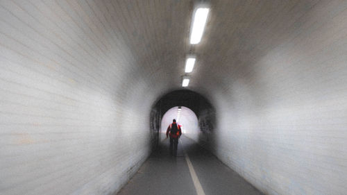 Rear view of person walking in tunnel