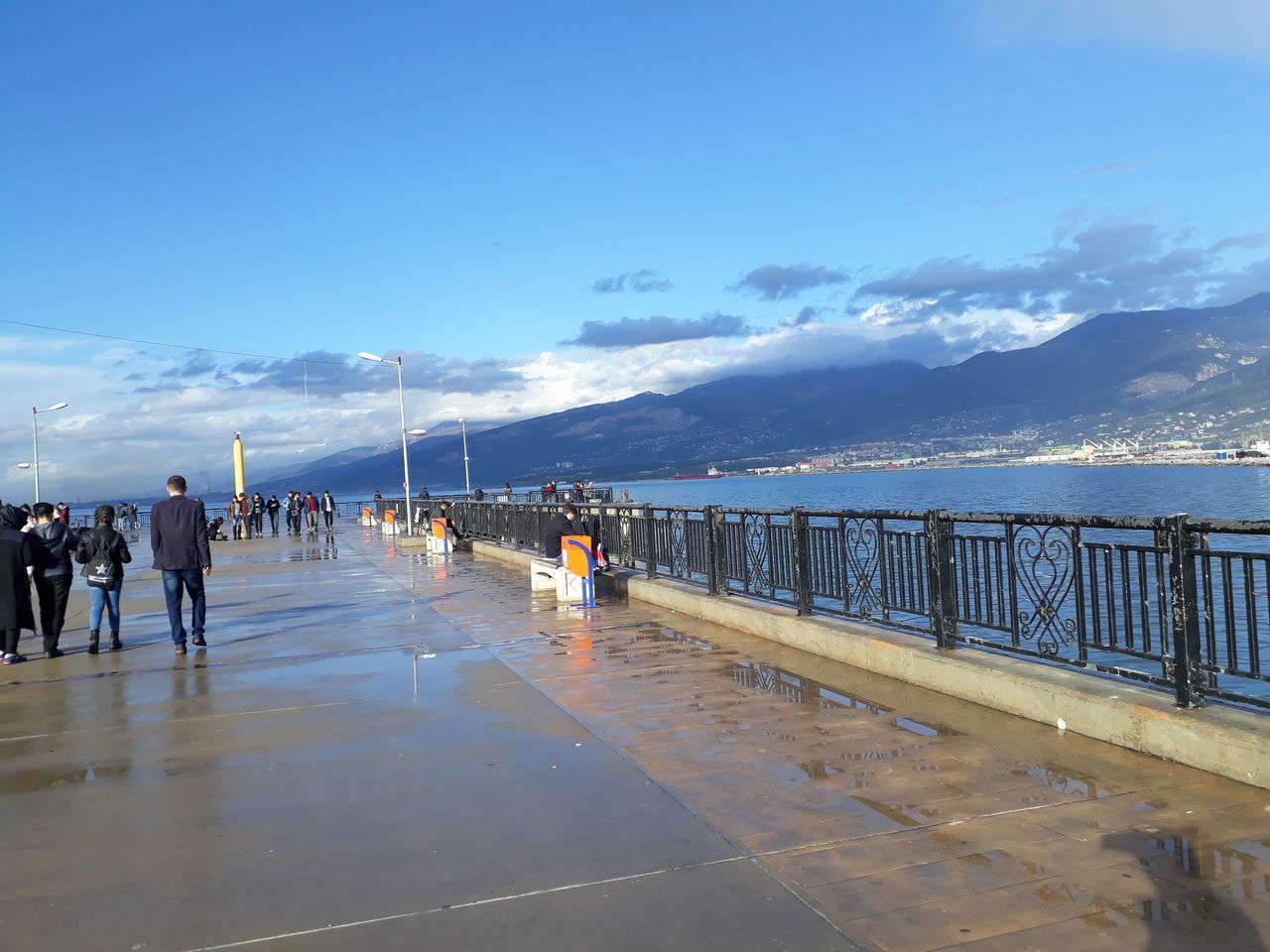 PEOPLE ON PIER BY SEA AGAINST BLUE SKY