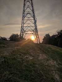 Electricity pylon on field against sky during sunset