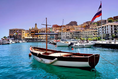 Sailboats moored on canal by buildings in city against sky