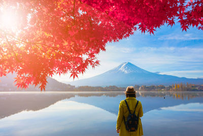 Rear view of woman standing by lake during autumn