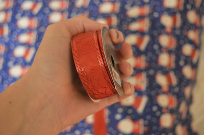 Festive red ribbon in hand. on a christmas background. fingers.nails. mole on hand. 