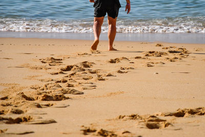Low section of man walking on beach