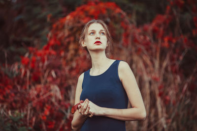 Young woman looking away while standing in autumn