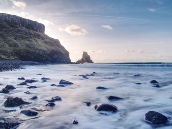 Sea stack silhouette by sunset sky. evening light on rocks, boulders and cliff face of talisker bay