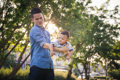 Smiling man playing with son in park