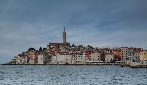 Buildings by sea against sky