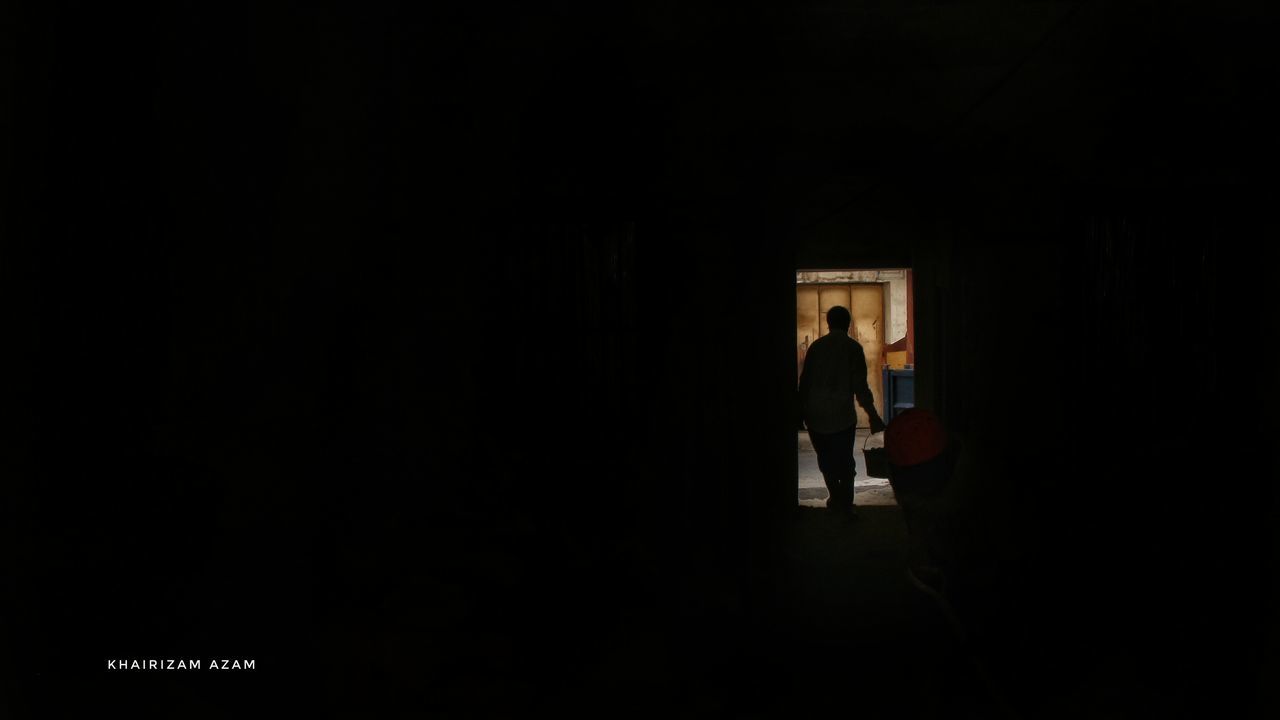 REAR VIEW OF MAN AND WOMAN STANDING IN DARK ROOM