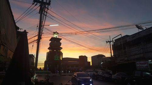 Cars on street in city against sky at sunset