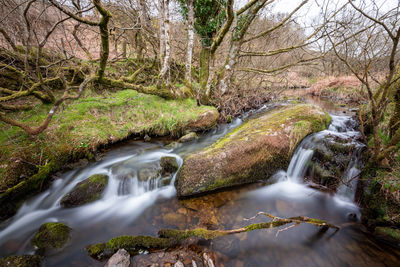 Long exposure of the weir water river flowing through the valley at robbers bridge in exmoor 