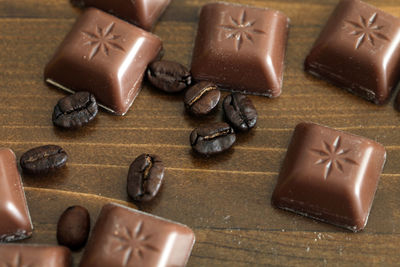 There are some delicious chocolate and coffee beans on the wooden table