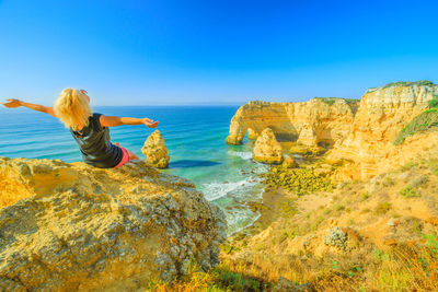 Woman with arms outstretched sitting at beach