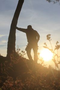 Silhouette man standing on field against sky during sunset