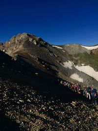 People on mountain against clear blue sky