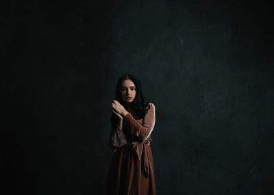 Young woman standing against black background