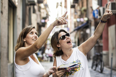 Female friends gesturing while standing on road