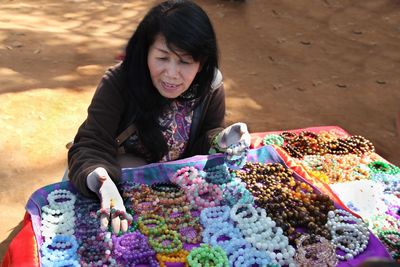 High angle view of woman choosing bead bracelets at market stall